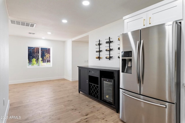 kitchen with white cabinetry, stainless steel fridge, and light hardwood / wood-style floors