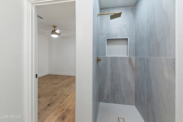 bathroom with ceiling fan, wood-type flooring, and tiled shower