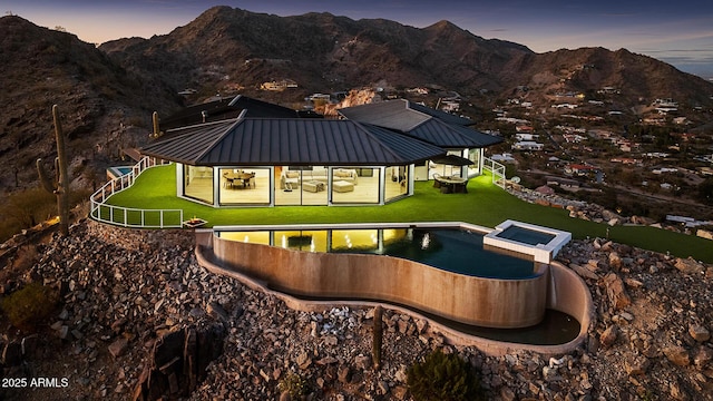 pool at dusk with a gazebo, a mountain view, and a yard