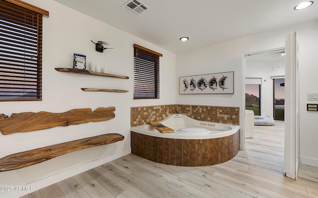 bathroom with hardwood / wood-style floors and tiled bath