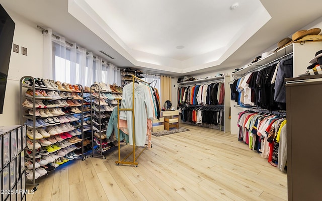 walk in closet with a raised ceiling and light wood-type flooring