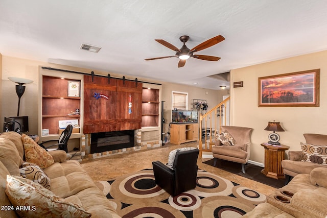 living room with a fireplace, visible vents, a barn door, a ceiling fan, and stairs