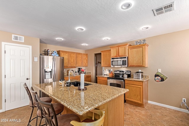 kitchen featuring visible vents, a breakfast bar area, appliances with stainless steel finishes, and a sink