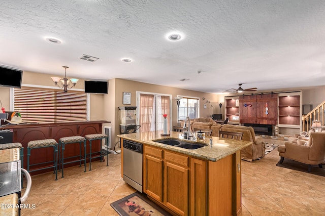 kitchen with light stone counters, visible vents, open floor plan, a sink, and dishwasher