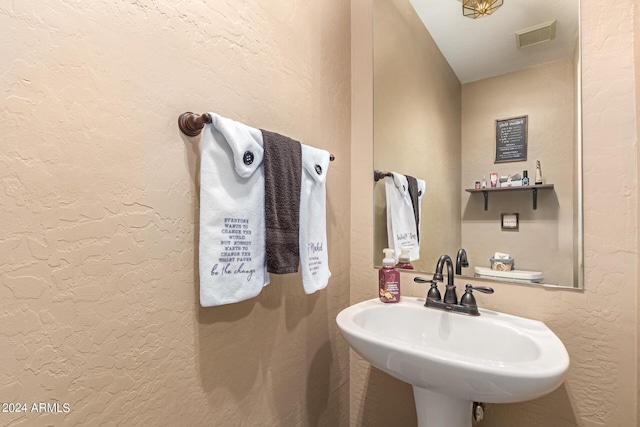 bathroom featuring a textured wall, a sink, and visible vents