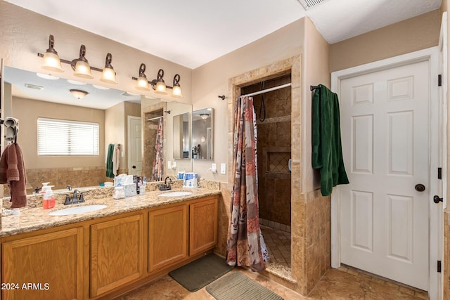 bathroom with visible vents, a sink, a tile shower, and double vanity