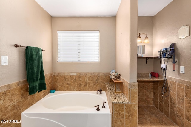 bathroom with wainscoting, tiled shower, tile walls, and a bath