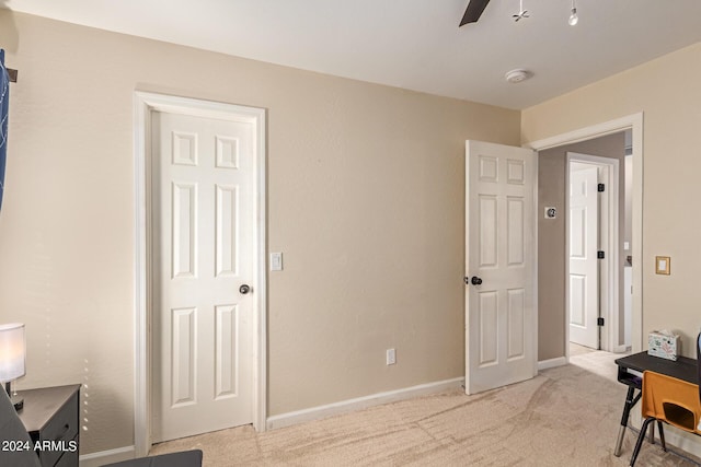 office space with a ceiling fan, light colored carpet, and baseboards