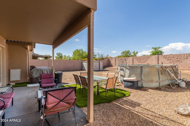 view of patio featuring an outbuilding, a storage unit, a fenced backyard, and a fenced in pool