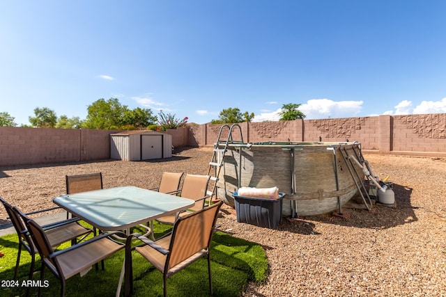 view of yard featuring outdoor dining space, a fenced backyard, an outdoor structure, and a storage shed