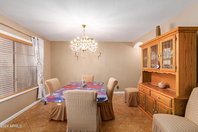 dining space with a chandelier, light tile patterned flooring, and baseboards