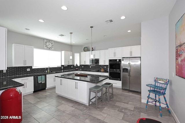 kitchen featuring a center island, white cabinets, stainless steel appliances, and decorative light fixtures