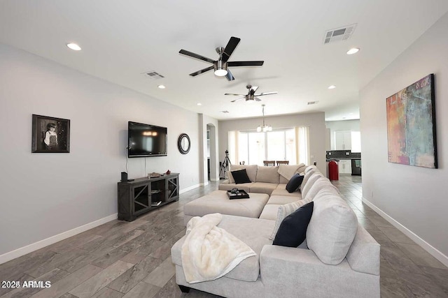 living room featuring ceiling fan with notable chandelier