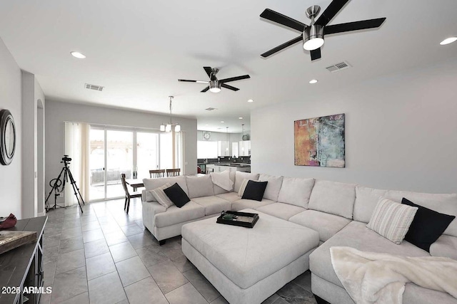 tiled living room featuring ceiling fan with notable chandelier