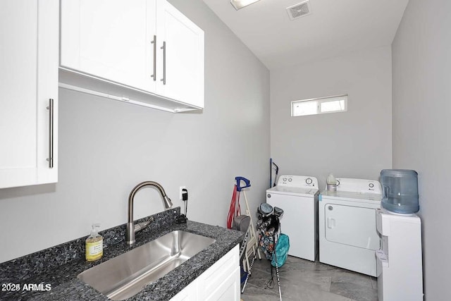 clothes washing area with washing machine and dryer, sink, and cabinets