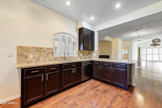 kitchen with kitchen peninsula, decorative backsplash, stainless steel dishwasher, sink, and hardwood / wood-style floors