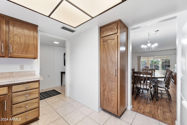 kitchen featuring pendant lighting, a notable chandelier, tile counters, and light tile patterned flooring