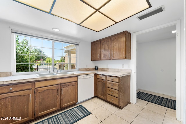 kitchen featuring white dishwasher, sink, and light tile patterned floors