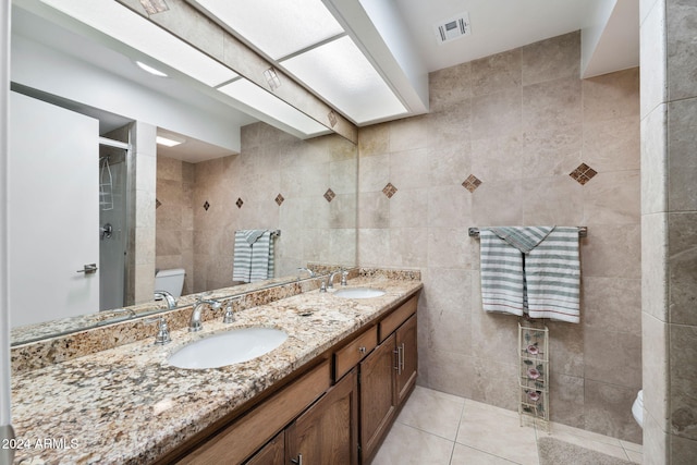 bathroom with walk in shower, toilet, tile patterned floors, tile walls, and vanity