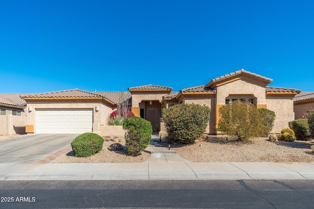 mediterranean / spanish house featuring a garage, concrete driveway, a tiled roof, and stucco siding