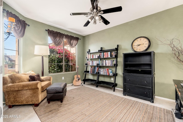 living area with baseboards and a ceiling fan