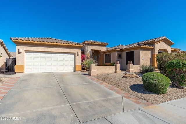 mediterranean / spanish home featuring driveway, an attached garage, a tiled roof, and stucco siding