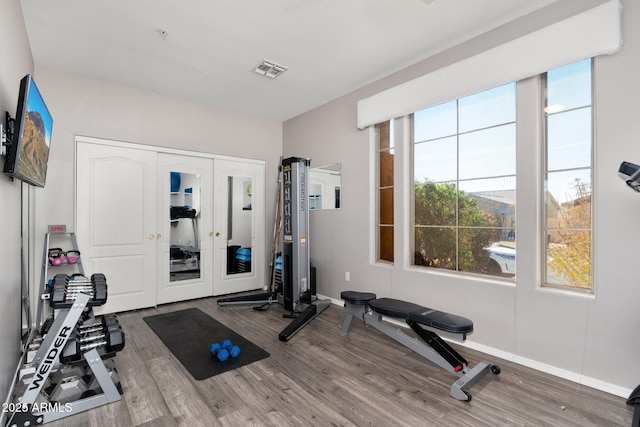 workout room with visible vents, baseboards, and wood finished floors