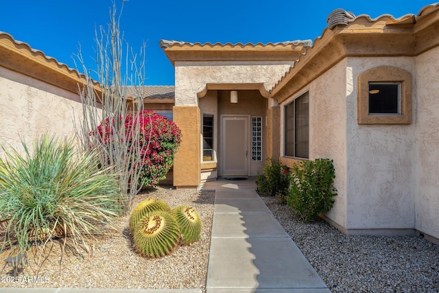 doorway to property featuring a tile roof and stucco siding