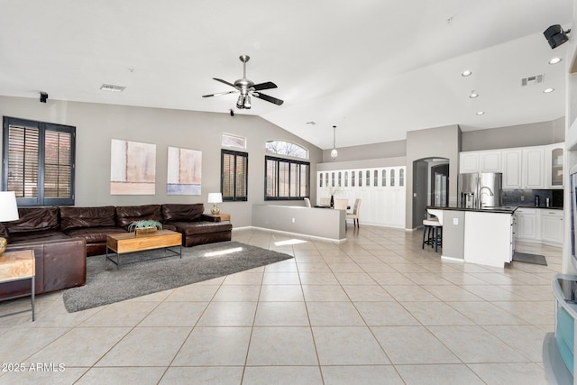 living area featuring lofted ceiling, visible vents, a ceiling fan, and light tile patterned flooring