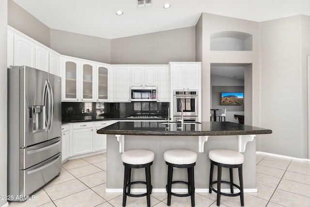 kitchen with appliances with stainless steel finishes, light tile patterned flooring, and white cabinetry