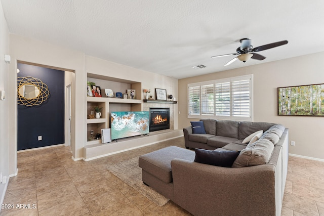 living room with a textured ceiling, built in features, and ceiling fan