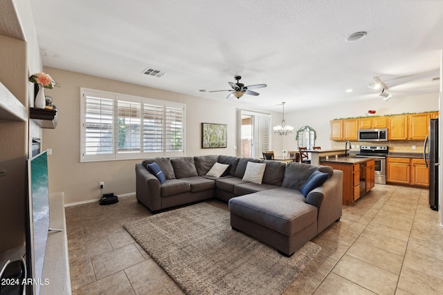 living room with light tile patterned flooring and ceiling fan with notable chandelier