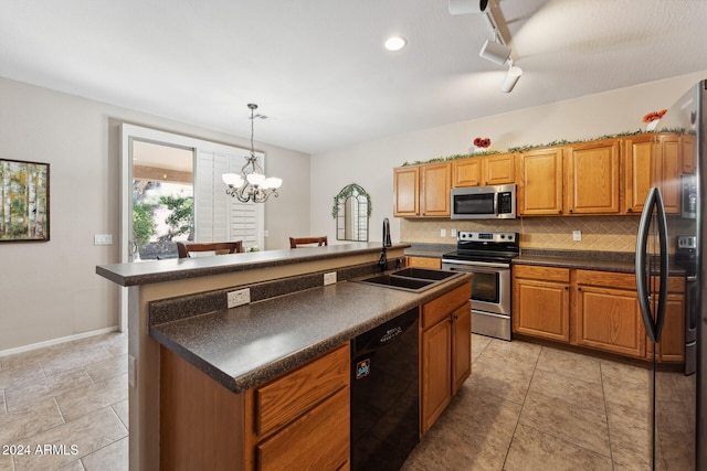 kitchen with an island with sink, stainless steel appliances, sink, pendant lighting, and a chandelier