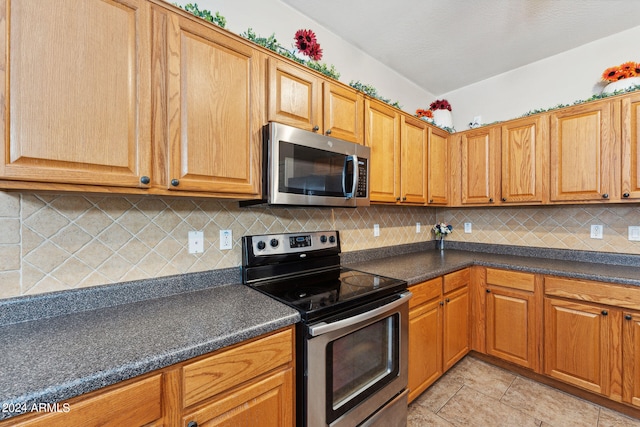 kitchen with appliances with stainless steel finishes, tasteful backsplash, and light tile patterned floors