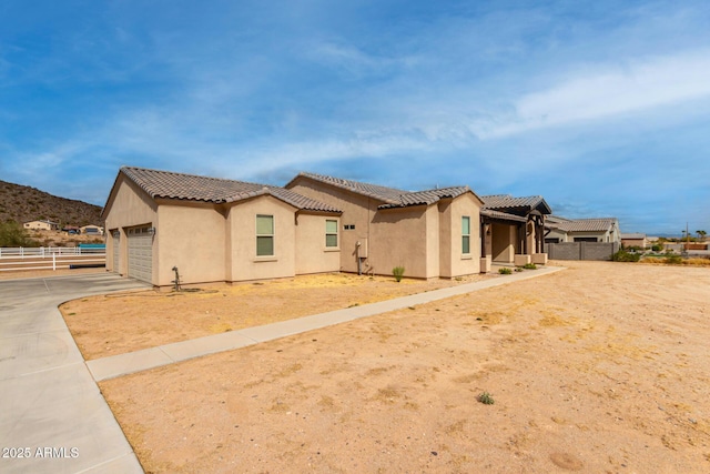 view of front of property featuring stucco siding, concrete driveway, an attached garage, fence, and a tiled roof