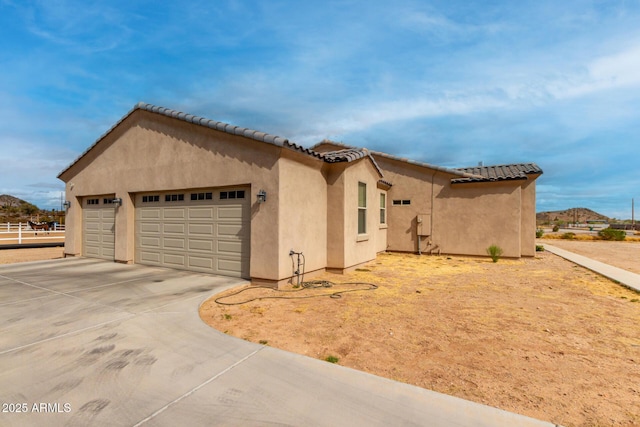 view of front of property featuring a garage, a tile roof, driveway, and stucco siding