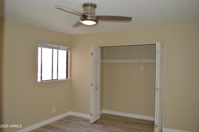 unfurnished bedroom featuring a ceiling fan, a closet, baseboards, and wood finished floors