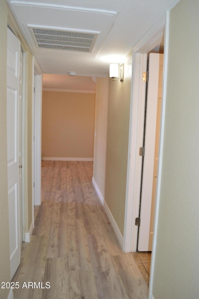 hall featuring visible vents, baseboards, and wood finished floors