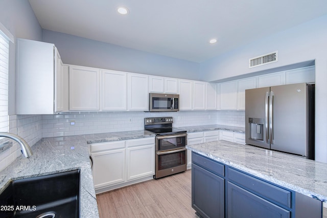 kitchen featuring stainless steel appliances, a sink, visible vents, and white cabinetry