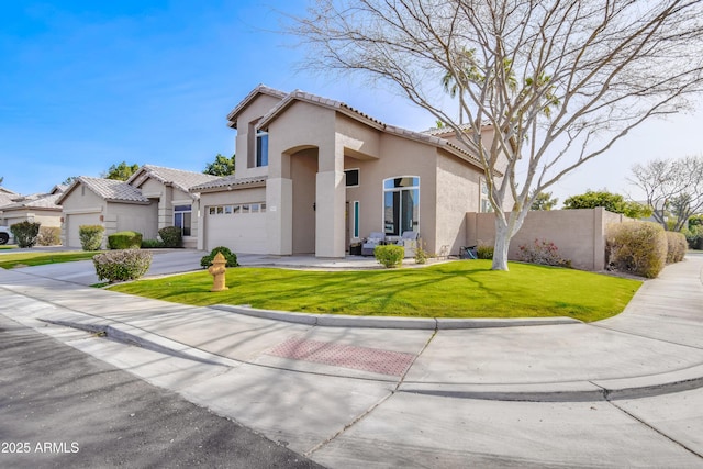 mediterranean / spanish house featuring fence, driveway, a tiled roof, stucco siding, and a front lawn