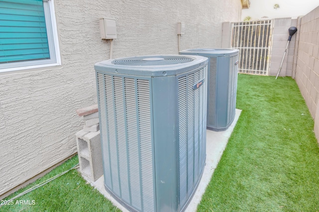 details featuring fence, central AC unit, and stucco siding