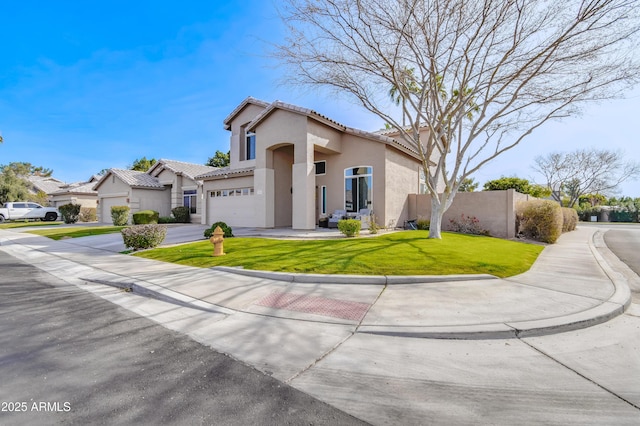 mediterranean / spanish-style house featuring driveway, stucco siding, a tiled roof, fence, and a front yard