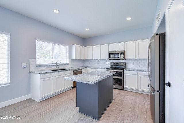 kitchen with appliances with stainless steel finishes, a center island, white cabinets, and a sink