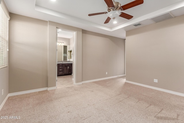 spare room featuring a tray ceiling, light carpet, ceiling fan, recessed lighting, and baseboards