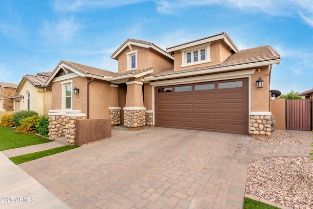 view of front of home featuring stone siding, decorative driveway, stucco siding, and a garage