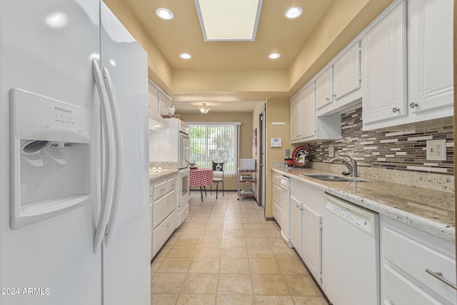 kitchen featuring sink, tasteful backsplash, white appliances, white cabinetry, and light stone countertops