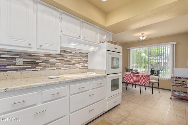 kitchen featuring light tile patterned flooring, backsplash, white appliances, and white cabinetry