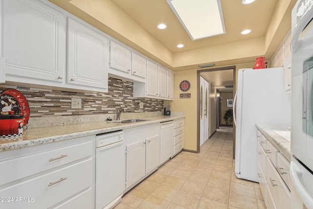 kitchen featuring light stone counters, white cabinets, sink, white appliances, and tasteful backsplash