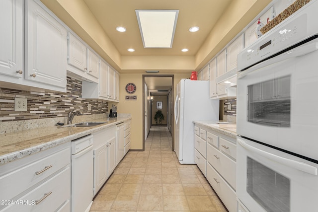 kitchen featuring light stone counters, decorative backsplash, white cabinets, white appliances, and sink