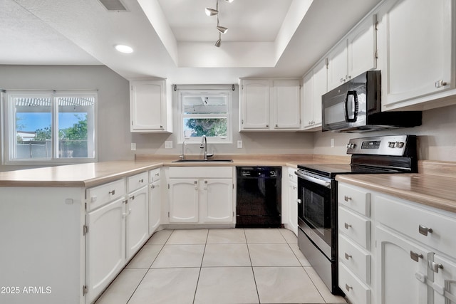 kitchen featuring a tray ceiling, a sink, white cabinets, a peninsula, and black appliances